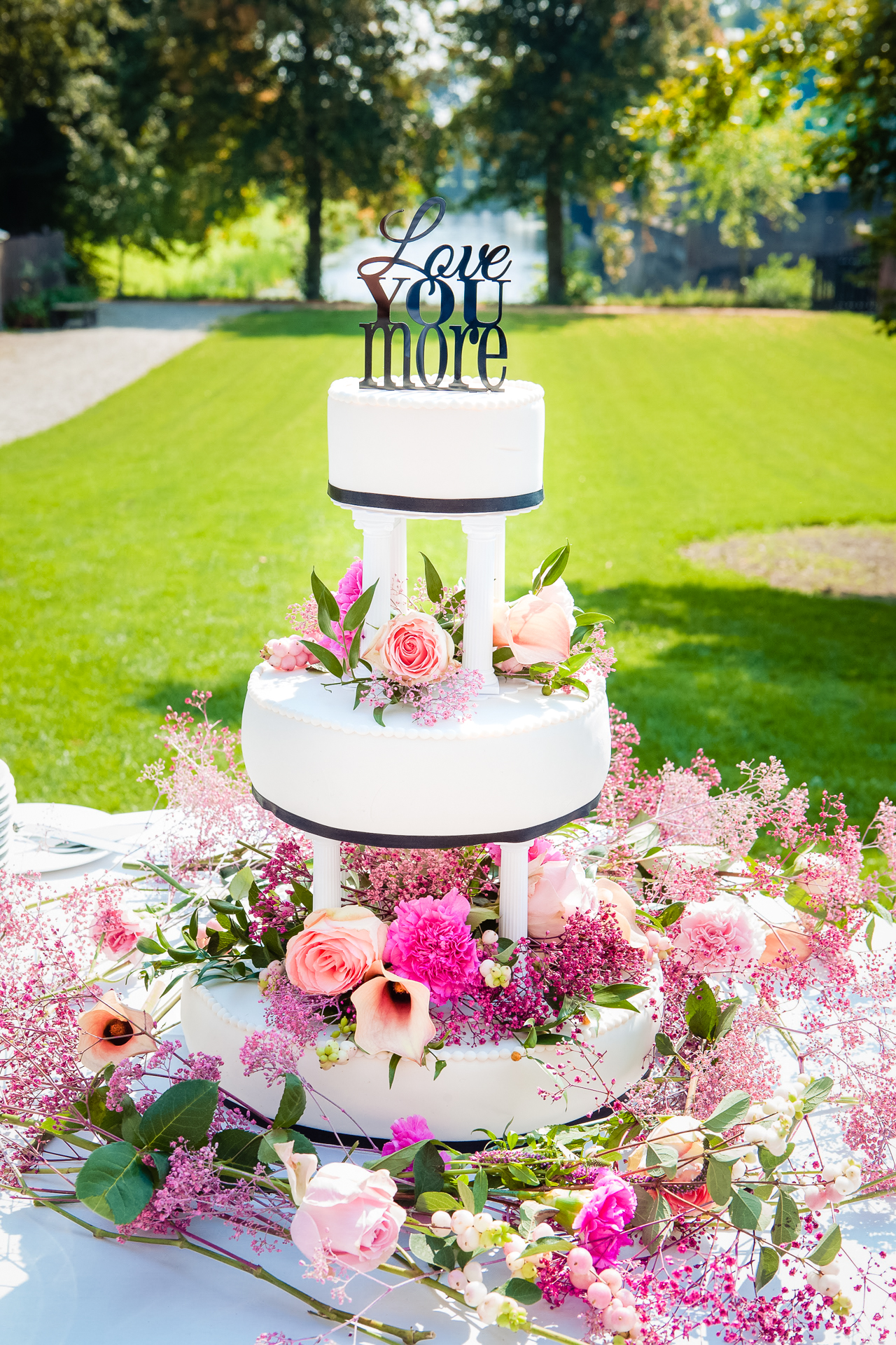 witte fondant bruidstaart in 3 lagen met roze bloemen er op