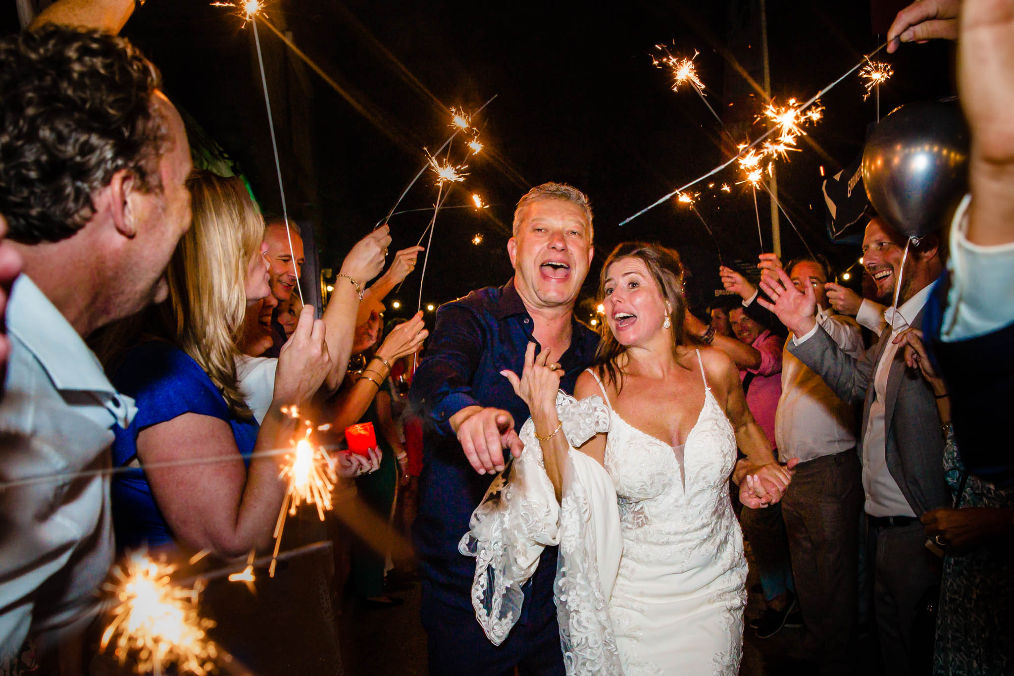 bruidspaar vertrekt bij het feest door een haag van gasten en sterretjes